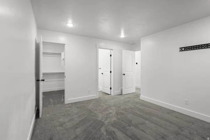 Unfurnished bedroom featuring a walk in closet and dark carpet