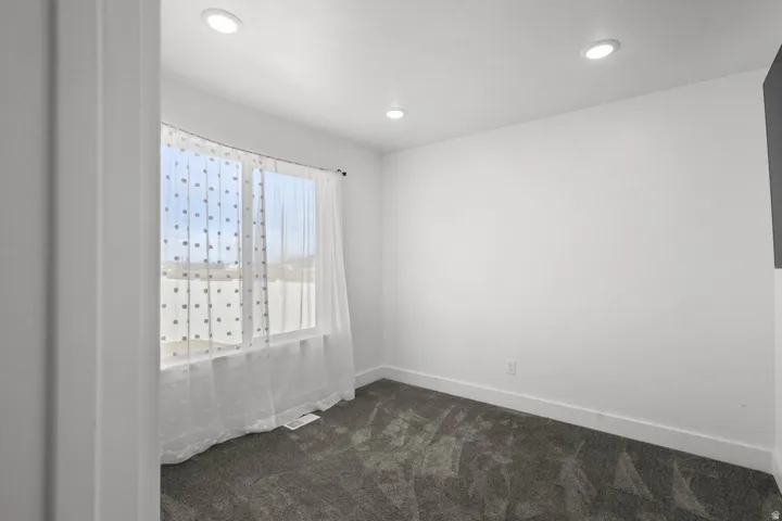 Empty room with dark colored carpet and recessed lighting