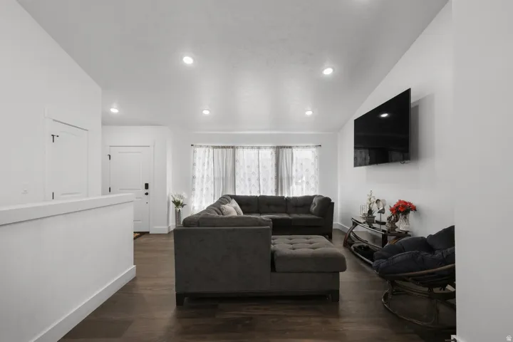 Living area featuring dark wood-style floors, lofted ceiling, and recessed lighting