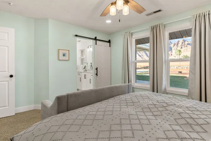Bedroom featuring a barn door, carpet floors, ceiling fan, ensuite bathroom, and recessed lighting