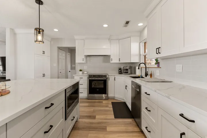Kitchen featuring stainless steel appliances, white cabinets, decorative light fixtures, light stone counters, and recessed lighting