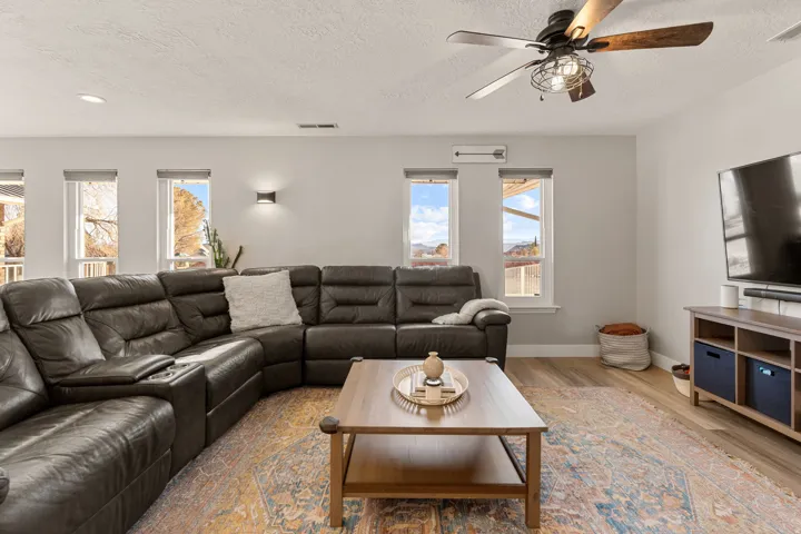 Living room with wood finished floors, a textured ceiling, and a ceiling fan