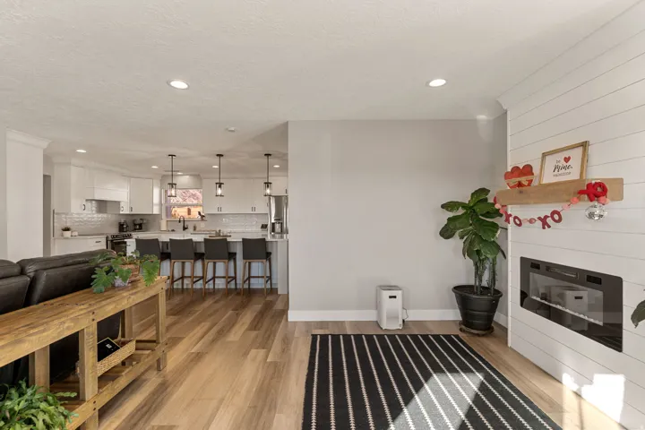 Living room with light wood finished floors, a glass covered fireplace, and recessed lighting