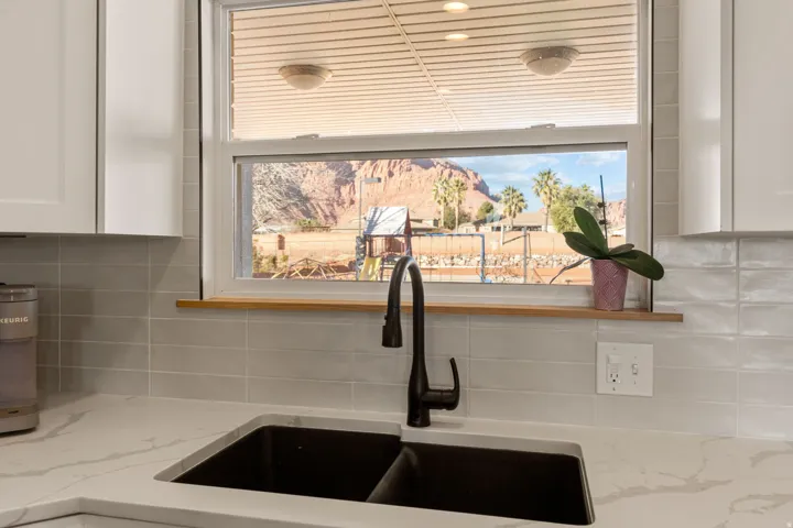 Kitchen view of decorative backsplash, white cabinets, and light stone countertops