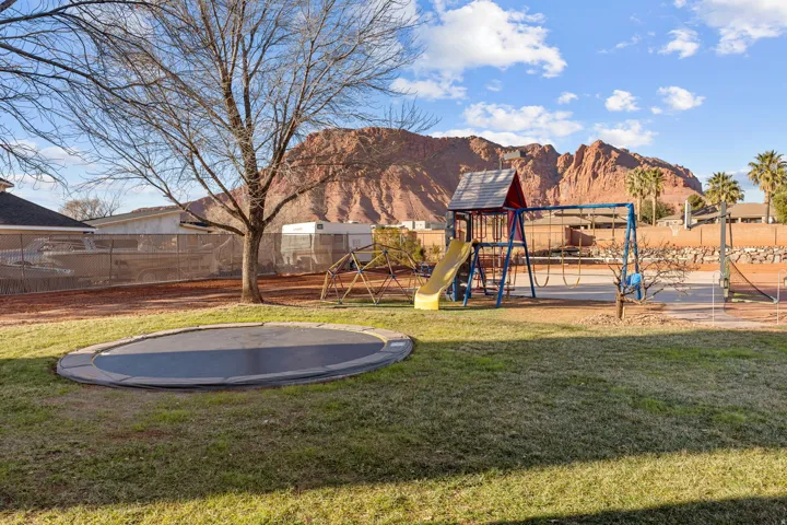View of yard with a trampoline, a playground, and a mountain view