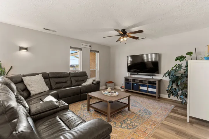 Living area with light wood-style floors, a textured ceiling, and ceiling fan