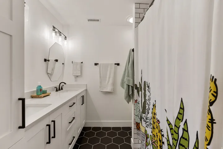 Bathroom featuring double vanity, curtained shower, and dark tile patterned flooring