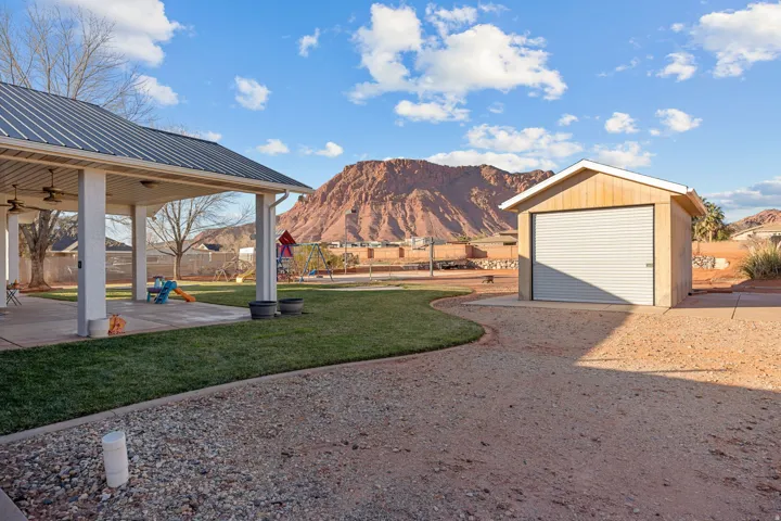 Fenced yard with a playground, an outdoor structure, a mountain view, and a patio area