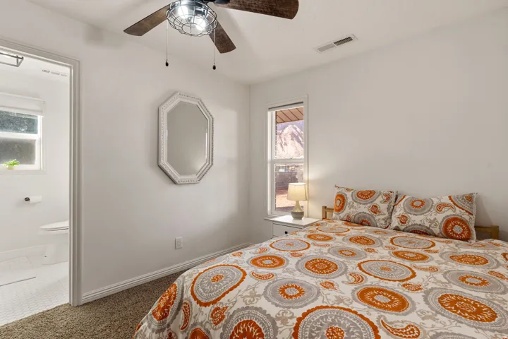 Bedroom with carpet floors, a ceiling fan, and connected bathroom