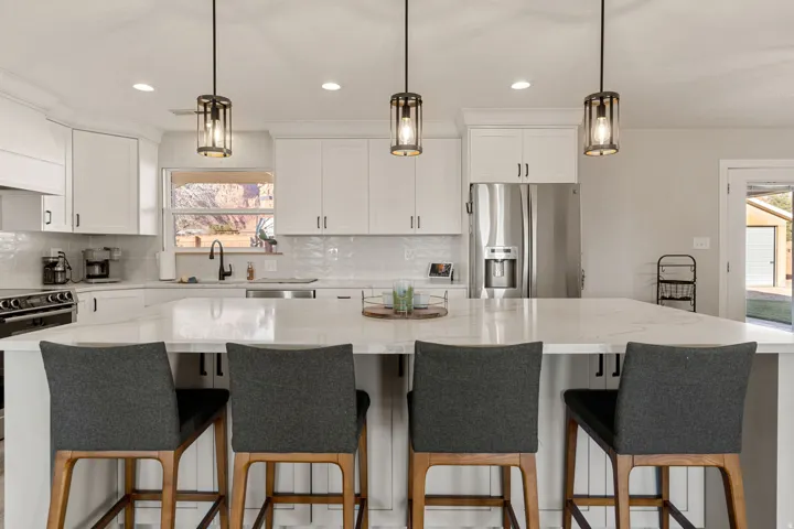Kitchen with appliances with stainless steel finishes, white cabinets, a large island, tasteful backsplash, and recessed lighting