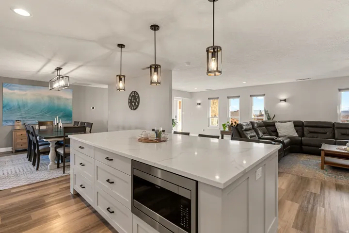 Kitchen with white cabinets, hanging light fixtures, stainless steel microwave, a center island, and recessed lighting