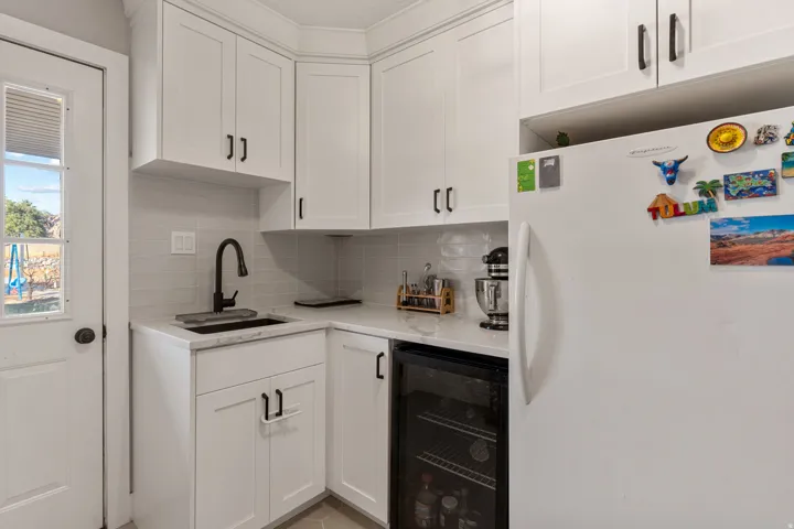 Bar area with freestanding refrigerator, beverage cooler, and white cabinetry