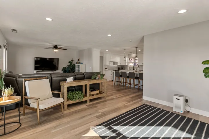 Living room featuring light wood-style floors, a ceiling fan, recessed lighting, and a textured ceiling