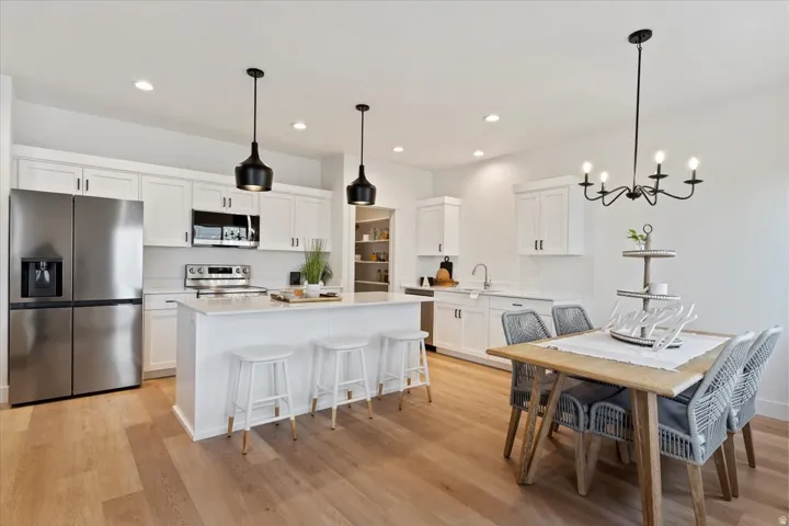 Kitchen featuring stainless steel appliances, white cabinets, a kitchen bar, pendant lighting, and recessed lighting