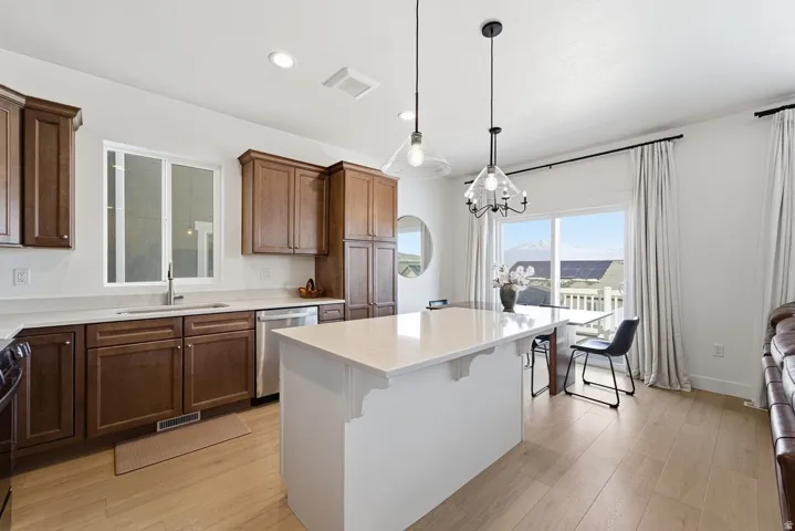 Kitchen with light wood-style floors, pendant lighting, dishwasher, a kitchen island, and recessed lighting