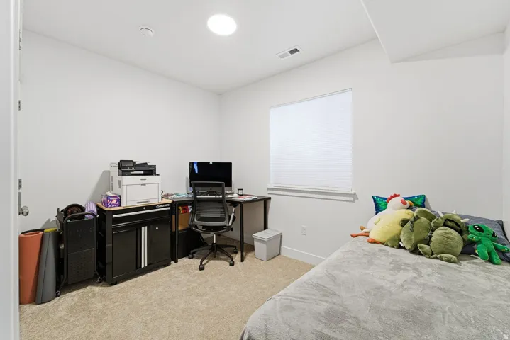 Bedroom with light carpet and a desk