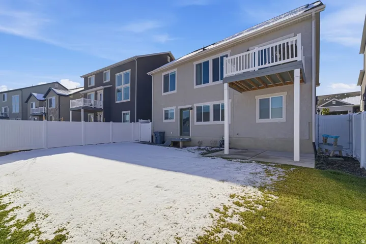 Rear view of property featuring a fenced backyard, a patio, a balcony, and stucco siding