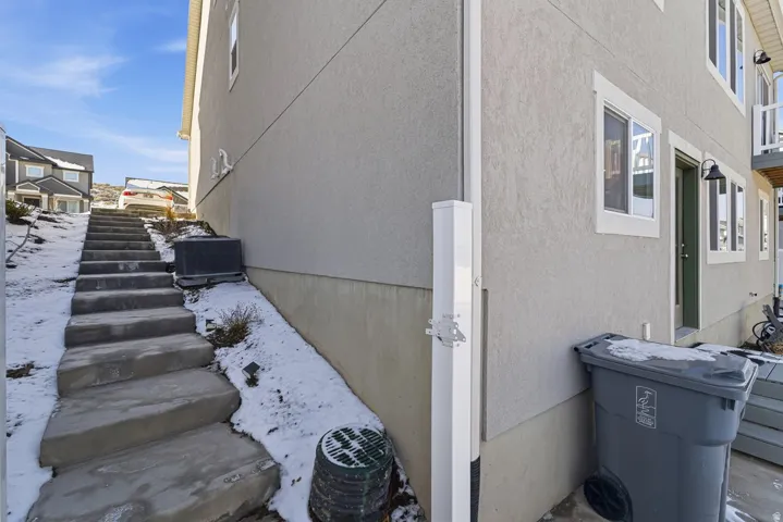 Snow covered property featuring stucco siding and stairs