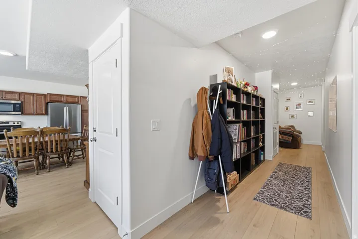 Hall with light wood-style flooring, a textured ceiling, and recessed lighting