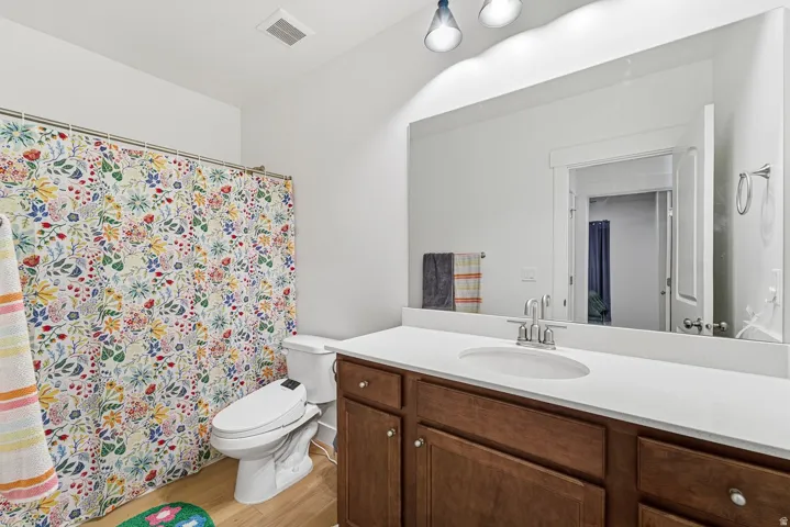Bathroom with vanity, a shower with curtain, and light wood finished floors