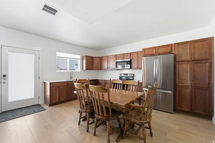 Kitchen with appliances with stainless steel finishes, light countertops, light wood-type flooring, and brown cabinets