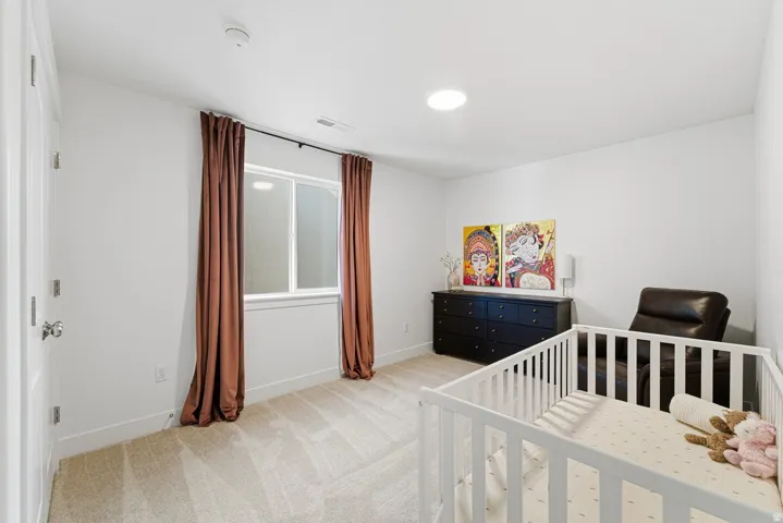 Bedroom with light colored carpet and a crib