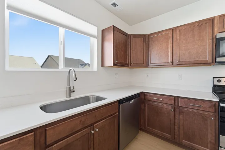 Kitchen with appliances with stainless steel finishes, light stone countertops, and light wood-type flooring
