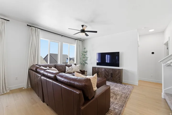 Living room with light wood-style flooring, a ceiling fan, and recessed lighting