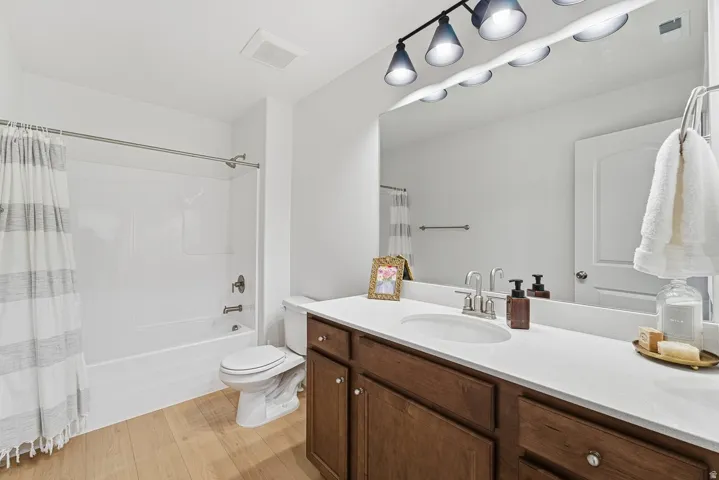 Bathroom with shower / bath combo with shower curtain, vanity, and light wood finished floors