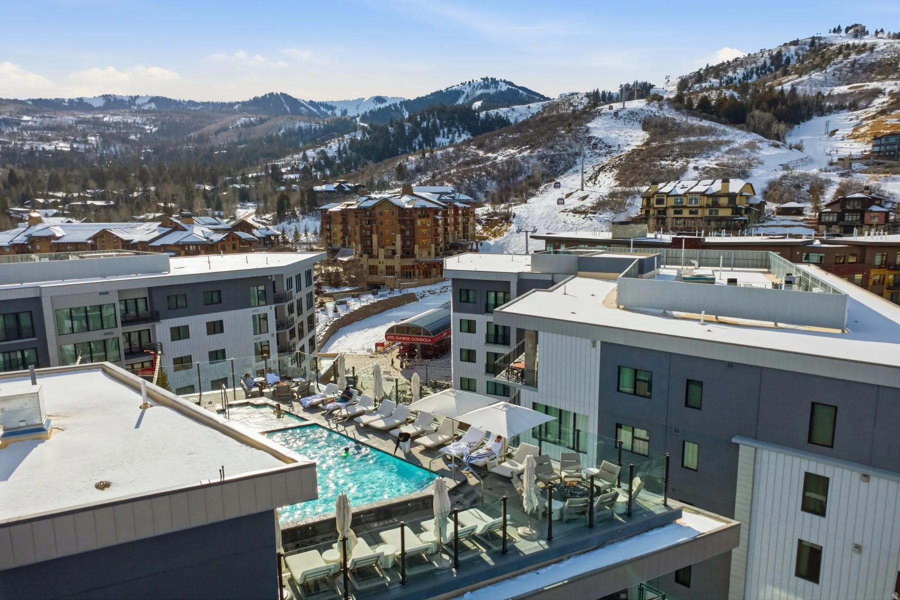 Snowy aerial view with a mountain view and view of pool area