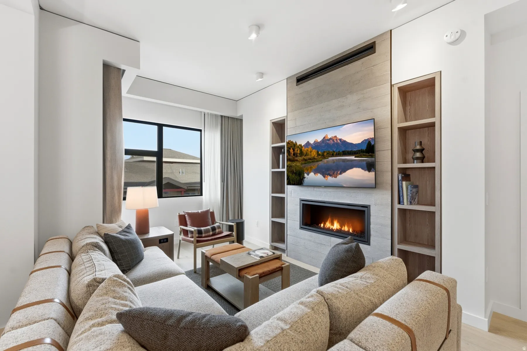 Living area with a fireplace, built in shelves, and light wood-style flooring
