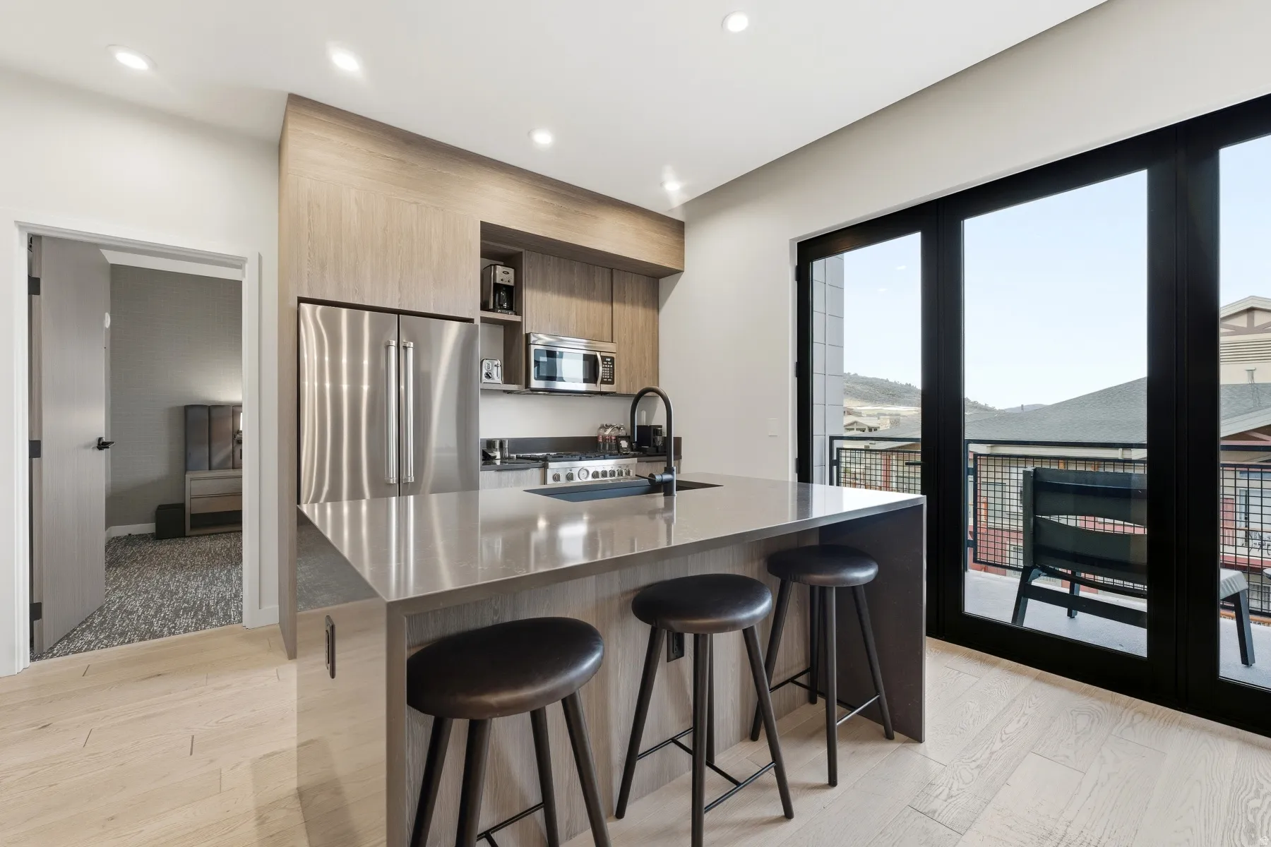 Kitchen featuring light wood finished floors, a kitchen bar, modern cabinets, appliances with stainless steel finishes, and recessed lighting