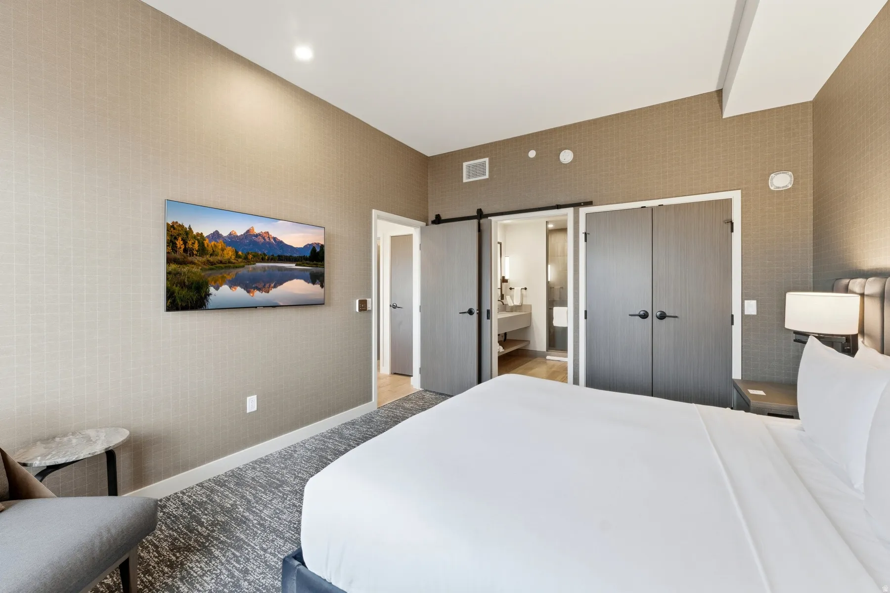 Bedroom featuring a barn door, a closet, and ensuite bathroom