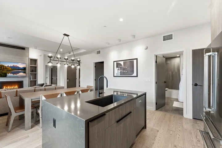 Kitchen with pendant lighting, a kitchen island with sink, modern cabinets, light wood-style floors, and high quality fridge