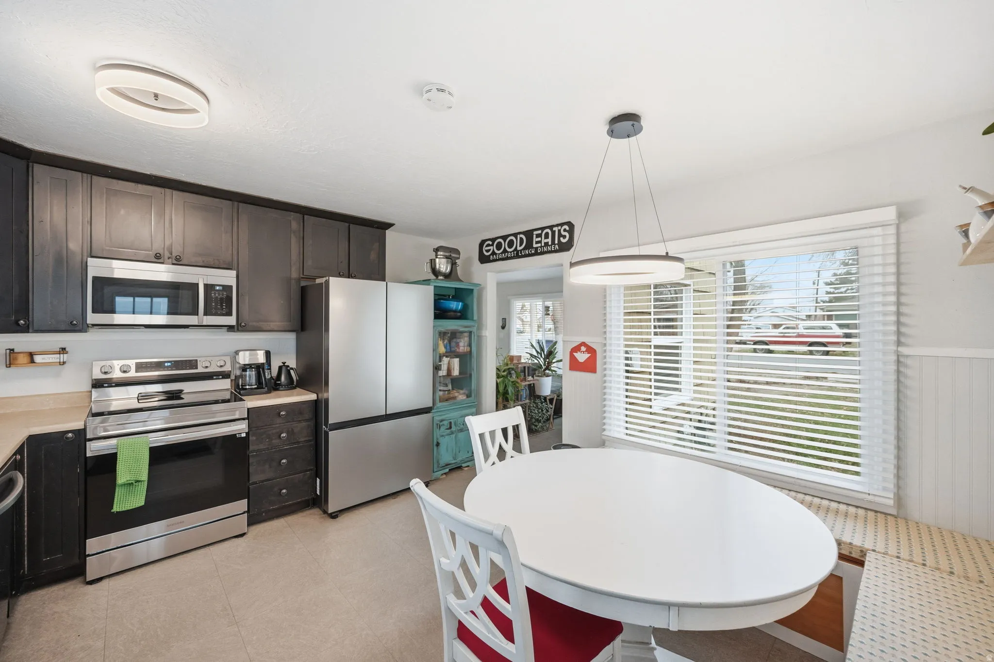 Kitchen featuring stainless steel appliances, light countertops, plenty of natural light, pendant lighting, and a wainscoted wall