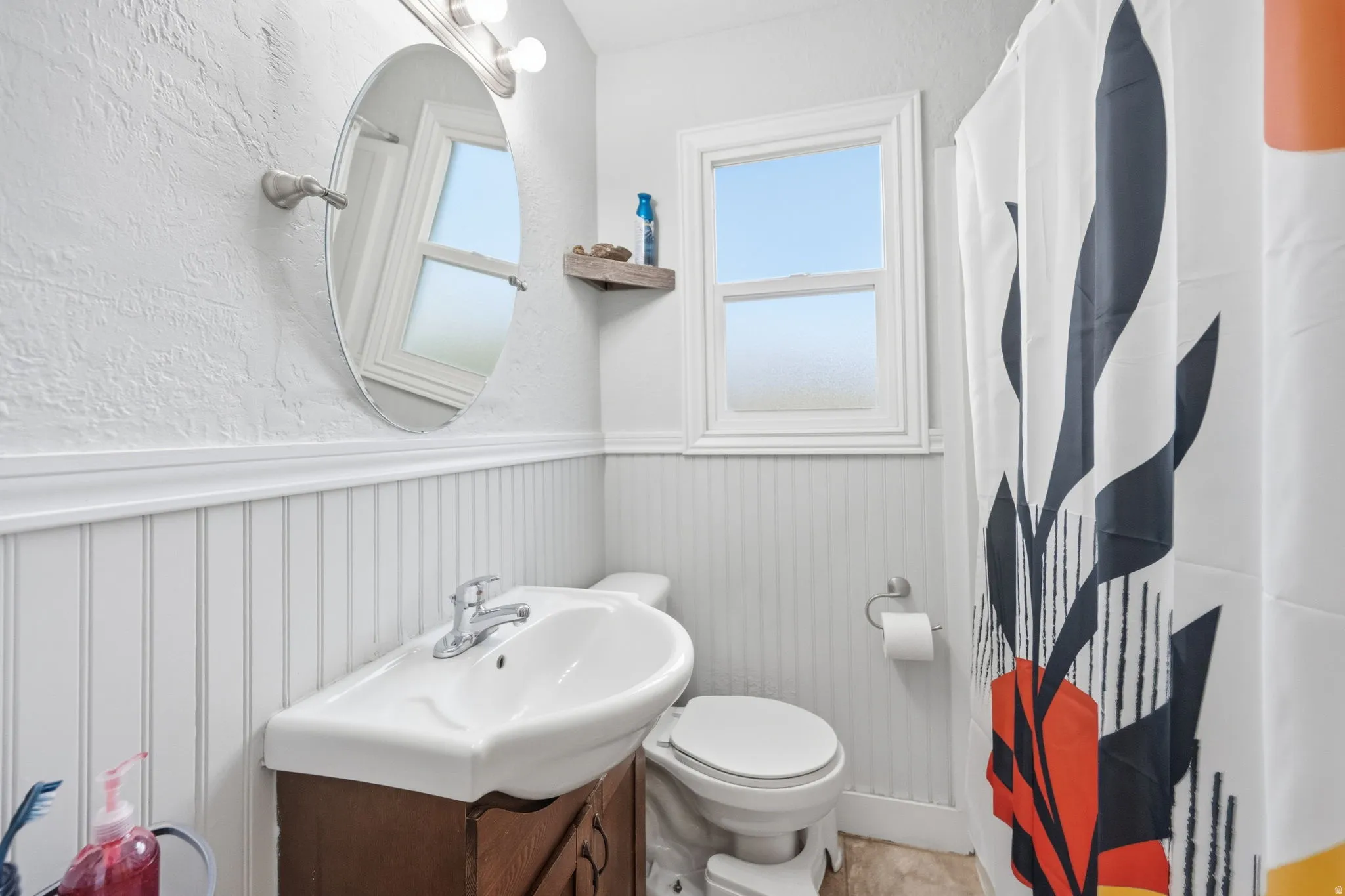 Bathroom with a textured wall, wainscoting, vanity, and a shower with shower curtain