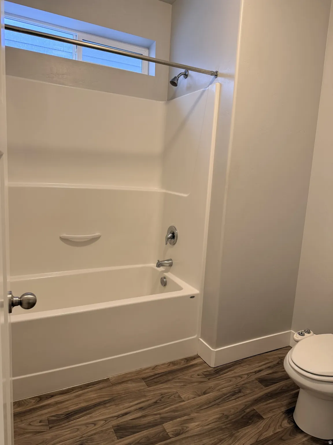 Bathroom with dark wood-type flooring and tub / shower combination