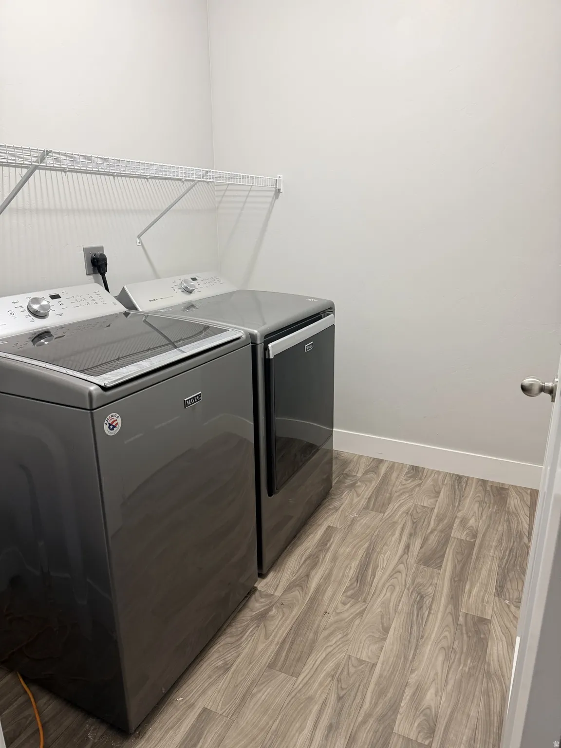 Laundry area with light wood finished floors and independent washer and dryer