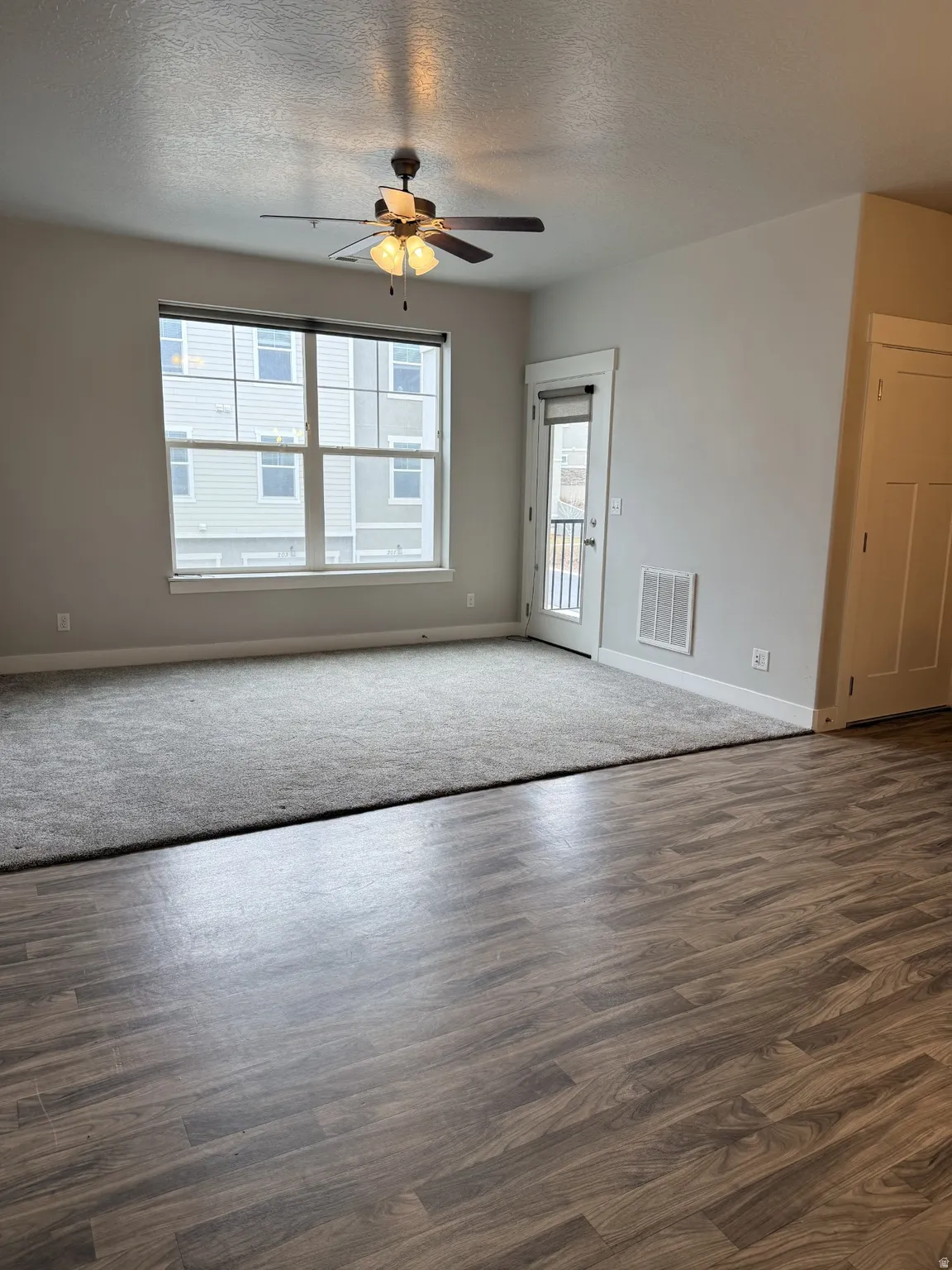 Empty room featuring a textured ceiling, a ceiling fan, and dark wood-style floors