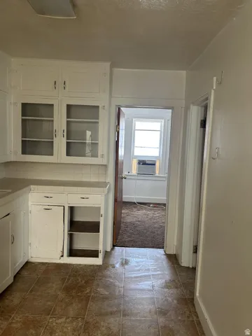 Kitchen featuring white cabinets, tile countertops, and glass insert cabinets