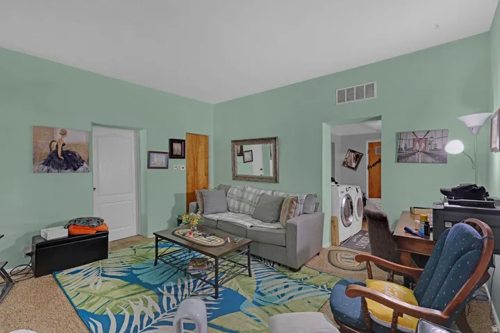 Living area featuring a desk, carpet floors, and washing machine and clothes dryer