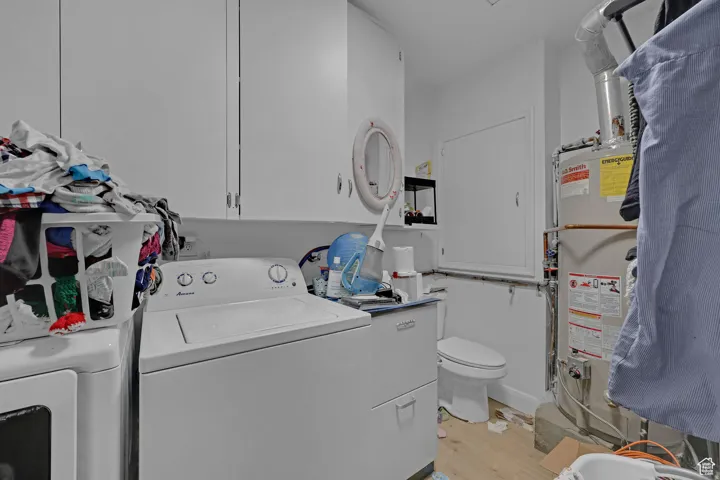 Laundry area with light wood finished floors, water heater, separate washer and dryer, and heating unit