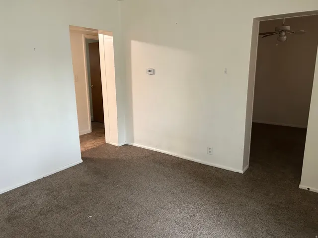 Unfurnished room featuring dark colored carpet and ceiling fan