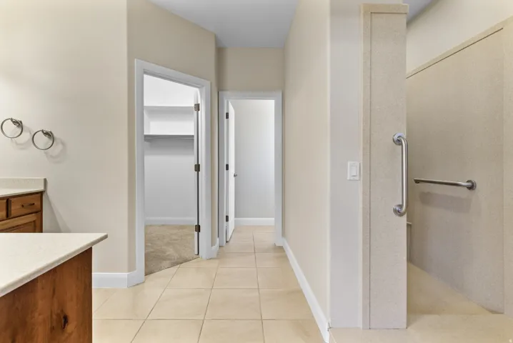 Full Primary bathroom featuring vanity, a walk in closet, light tile patterned floors, and a walk in shower