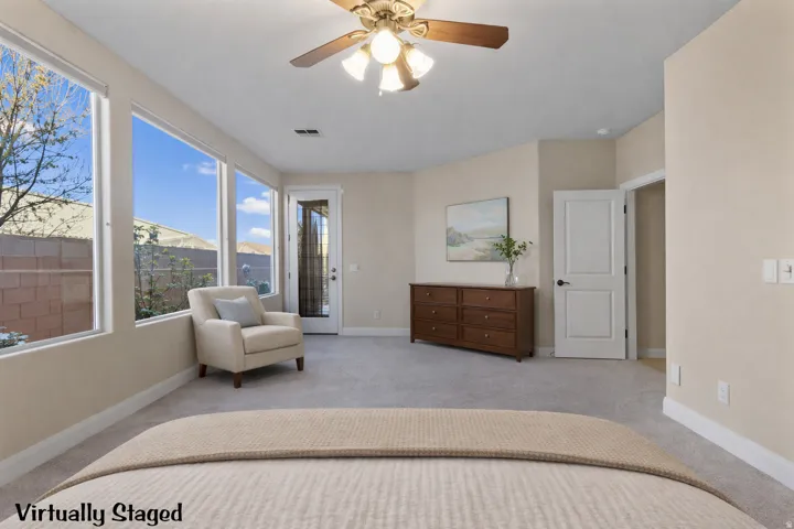 Primary bedroom with ceiling fan and access to exterior. Virtually Staged.