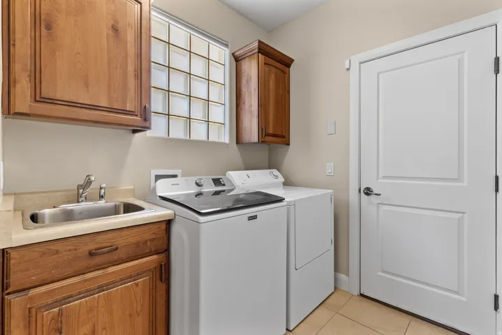 Washroom featuring cabinet space, separate washer and dryer, and light tile patterned floors