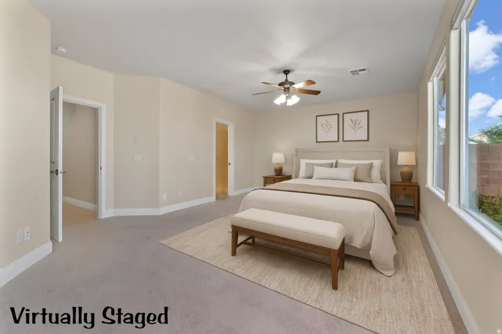Primary bedroom featuring light colored carpet and a ceiling fan. Virtually Staged.