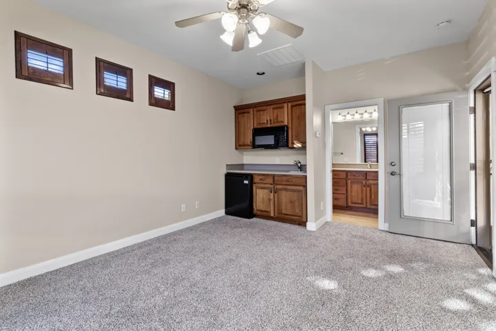 Casita featuring light colored carpet, black appliances, brown cabinetry, light countertops, and ceiling fan