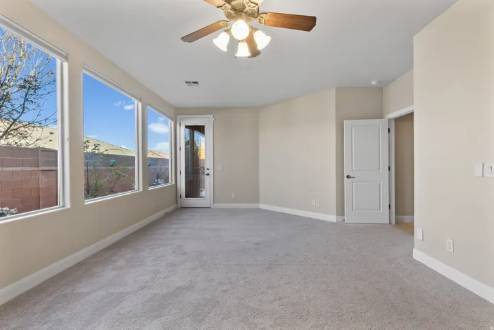 Primary bedroom with light carpet and a ceiling fan
