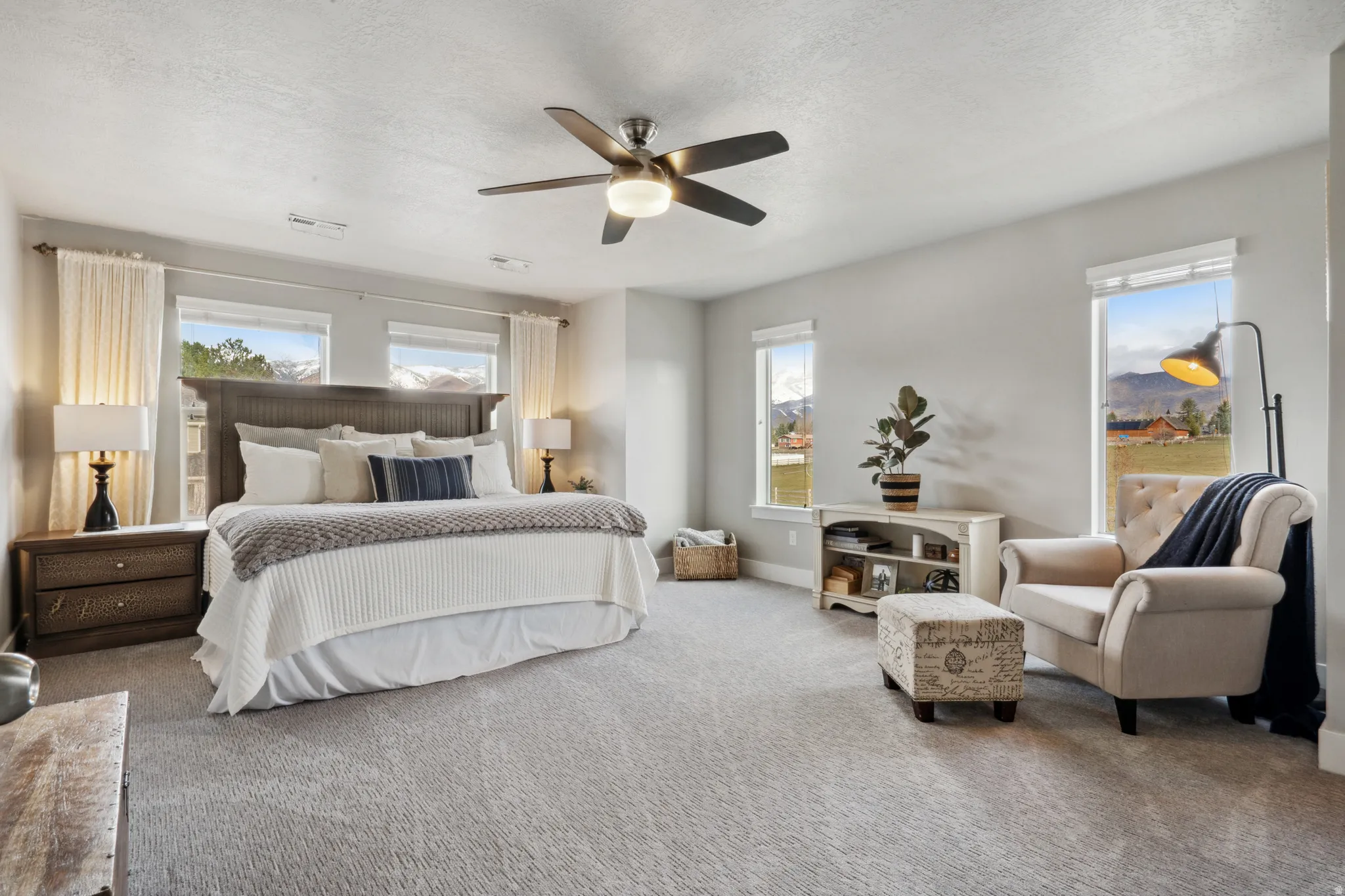 Carpeted primary bedroom featuring a textured ceiling and a ceiling fan